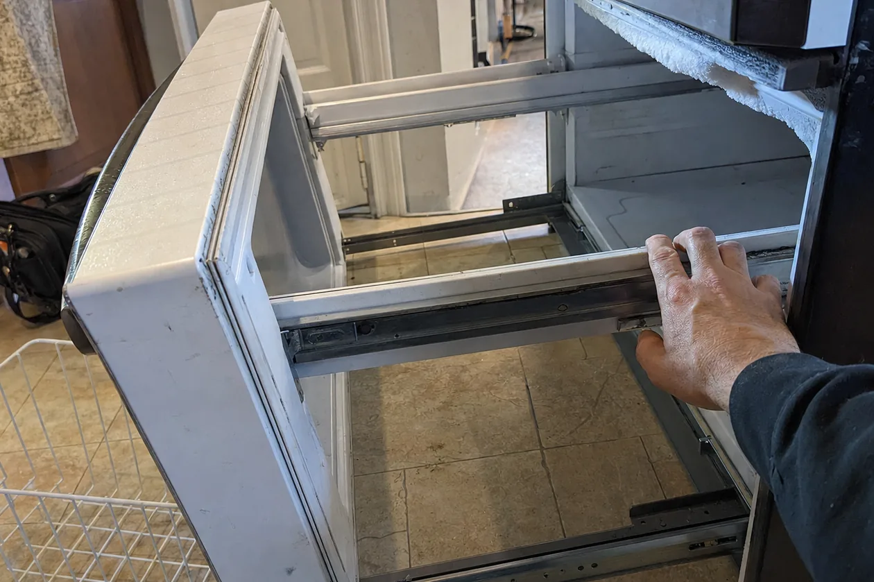 The empty rails of a bottom-freezer drawer with the basket lifted out